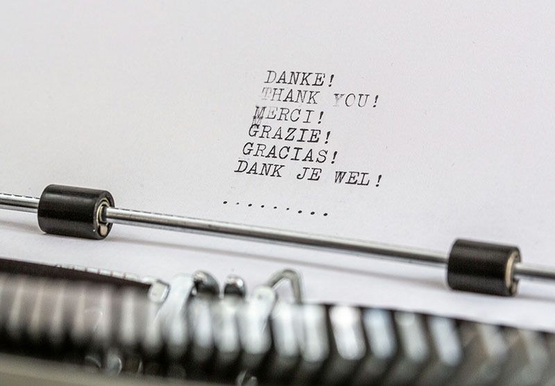 Closeup of typewriter and the paper feed has Thank You written in multiple languages