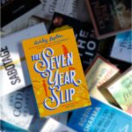 Pile of books with The Seven Year Slip by Ashley Poston in focus