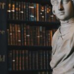 Bust in front of dimly lit bookshelves