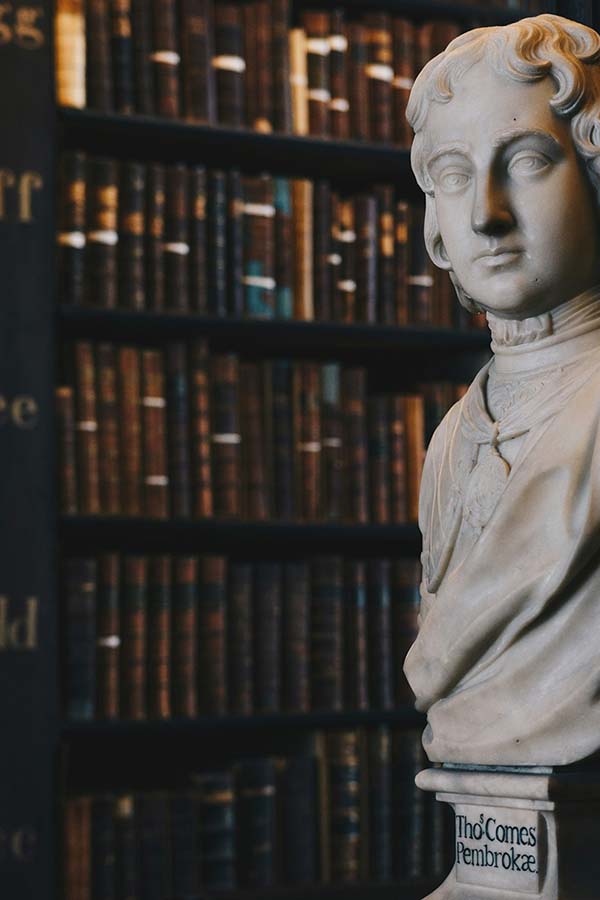 Bust in front of dimly lit bookshelves