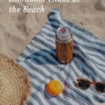 Beach blanket with drink, orange, sunglasses, and beach hat