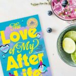 Flatlay of The Love of My Afterlife by Kirsty Greenwood next to summer cocktails